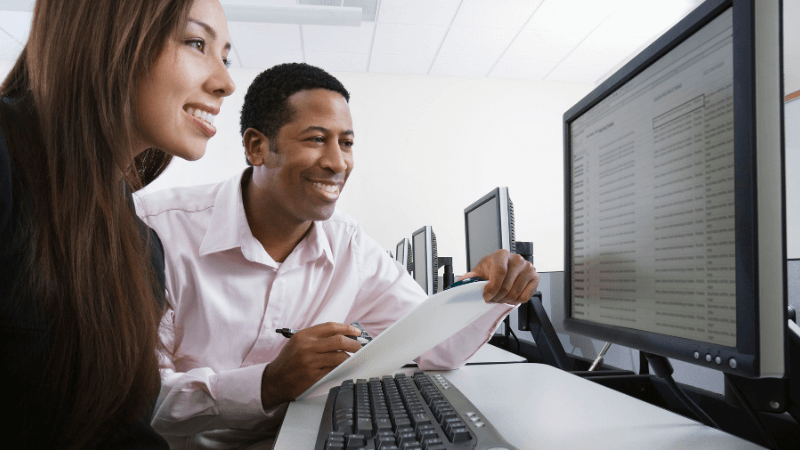 Two people working on a computer to build their Google ads.